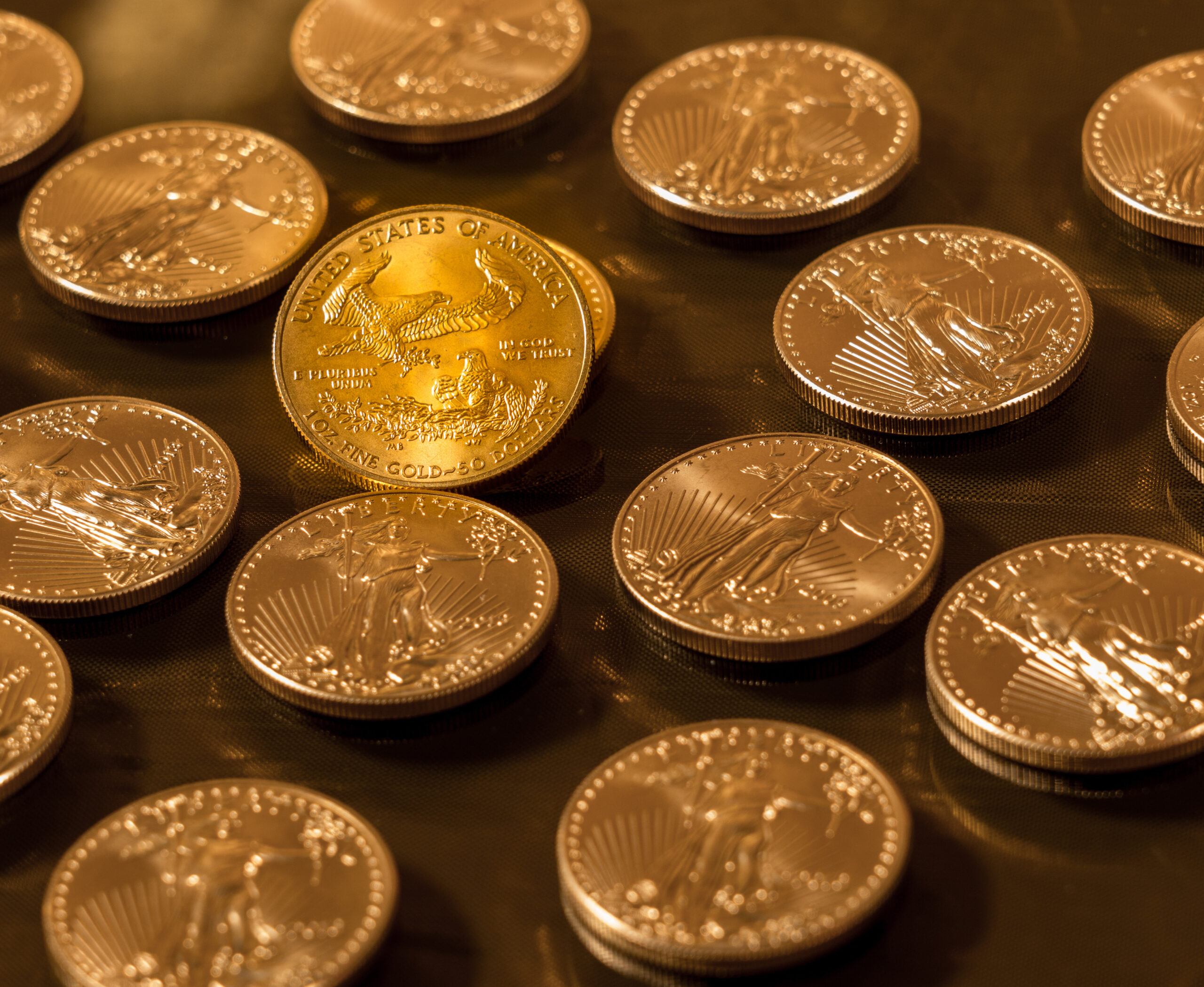 Gold Eagle one ounce coin against a golden background of other coins with focus on the Eagle symbol