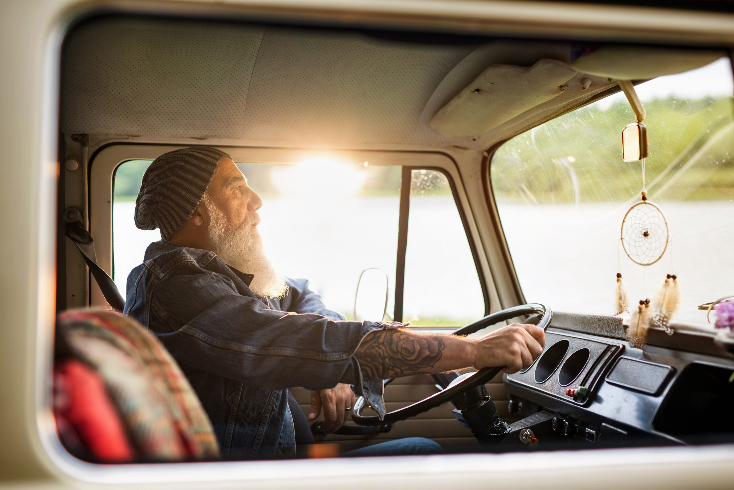 Senior Hipster Driving A Van By Countryside. He Is tattooed